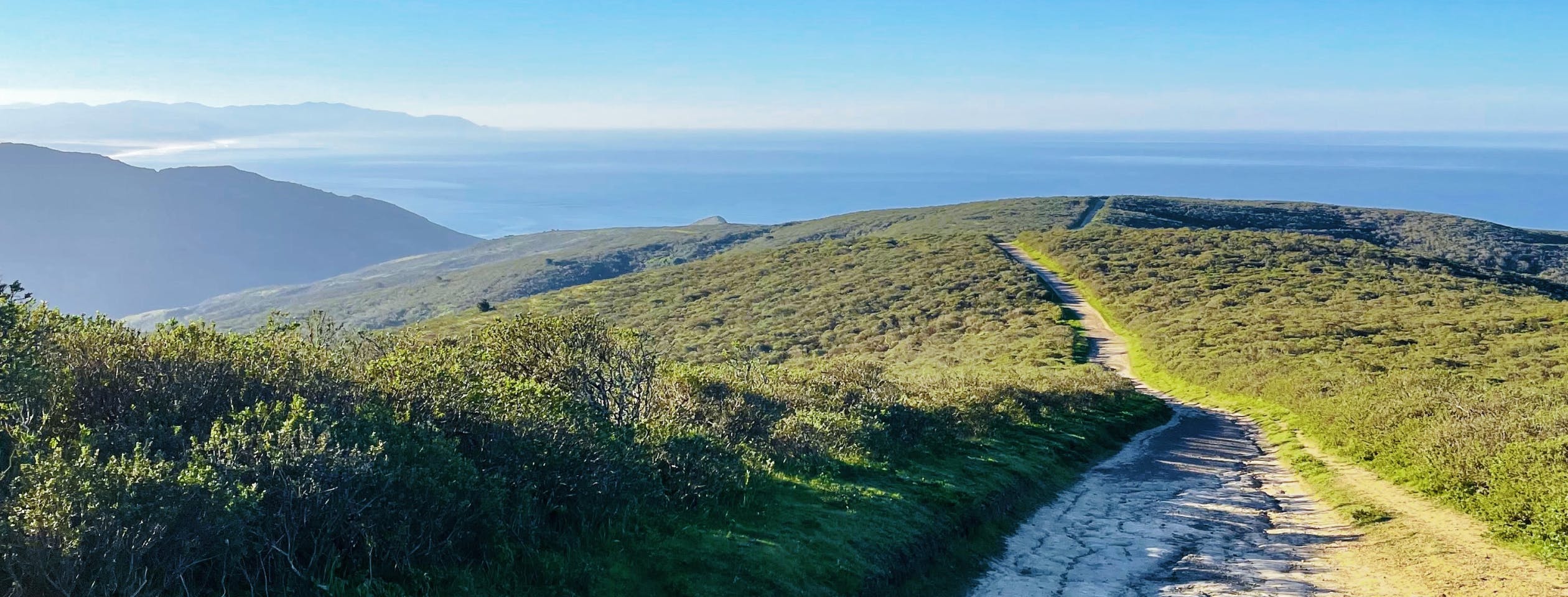 California running trail in the hills with the ocean in the background.